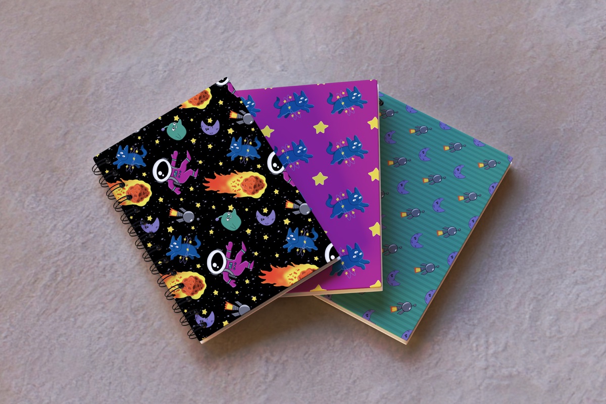 Three notebooks covered in Galactic Boom patterns